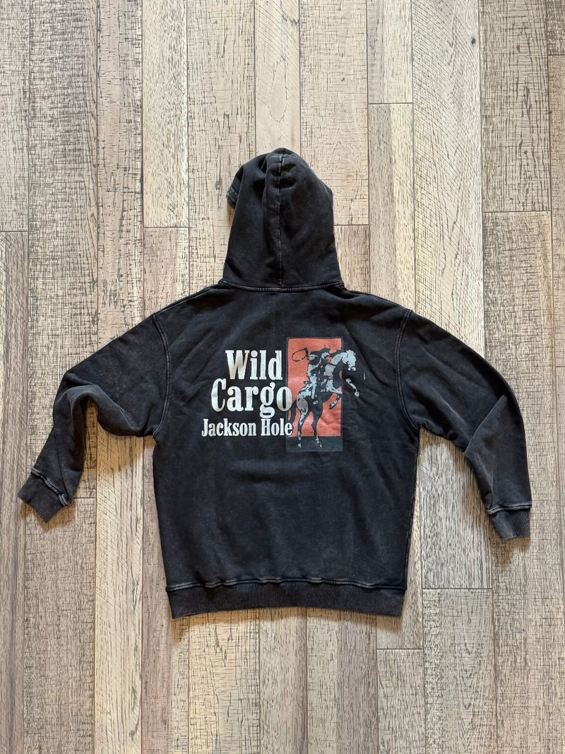 Black hoodie with 'Wild Cargo Jackson Hole' print on a wooden floor